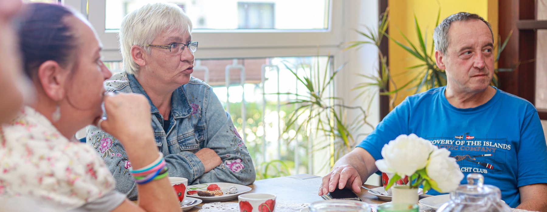 Drei Menschen sitzen an einem Tisch und unterhalten sich.